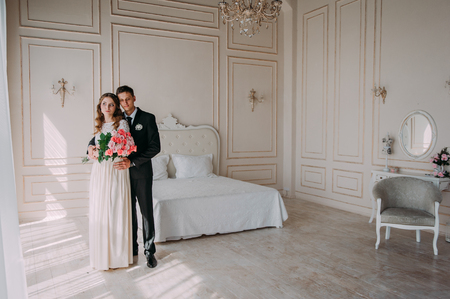 cute wedding couple in the interior of a classic studio decorated. hey kiss and hug each otherの写真素材