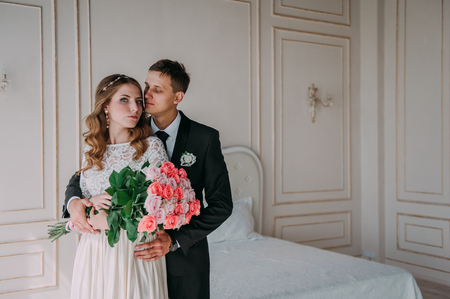 cute wedding couple in the interior of a classic studio decorated. hey kiss and hug each otherの写真素材