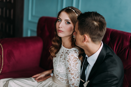 cute wedding couple in the interior of a classic studio decorated. hey kiss and hug each otherの写真素材