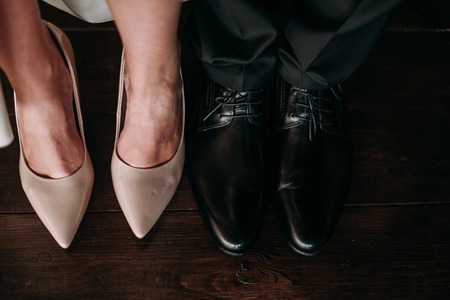 Love and happiness on wedding day. Closeup of bride's and groom's feet and shoes and wooden decoration 'love' in their hands.の写真素材