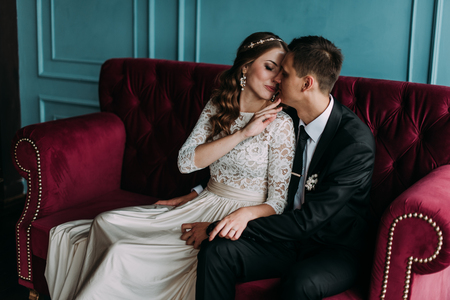 cute wedding couple in the interior of a classic studio decorated. hey kiss and hug each otherの写真素材