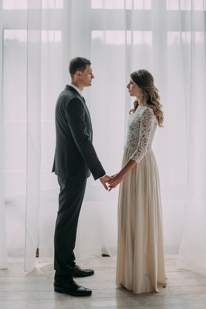 cute wedding couple in the interior of a classic studio decorated. hey kiss and hug each otherの写真素材