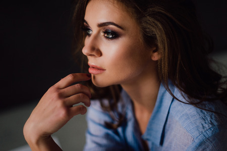 Portrait of sexy young woman posing in studio at natural light, wearing blue shirt, has good and healthy fitの写真素材