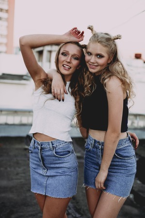 lifestyle and people concept: Fashion portrait of two stylish girls best friends wearing jeans skirts, outdoors. Happy summer time for fun. Concept of 90sの写真素材