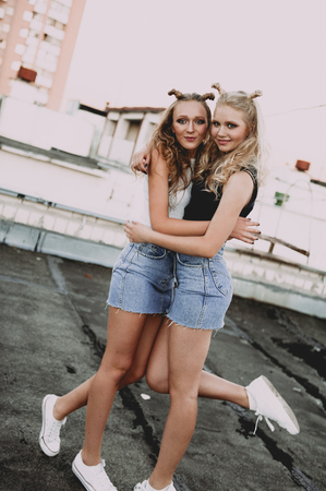 lifestyle and people concept: Fashion portrait of two stylish girls best friends wearing jeans skirts, outdoors. Happy summer time for fun. Concept of 90sの写真素材