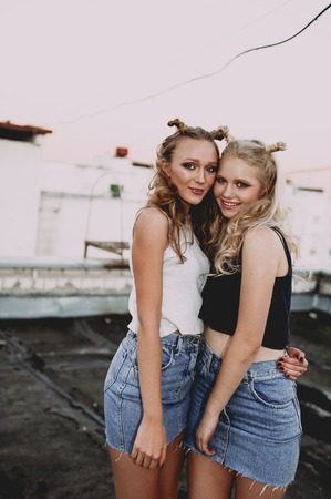 lifestyle and people concept: Fashion portrait of two stylish girls best friends wearing jeans skirts, outdoors. Happy summer time for fun. Concept of 90sの写真素材