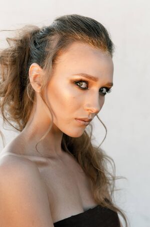Glamour portrait of young fashion woman face with bright evening golden make up for party. Warm...
