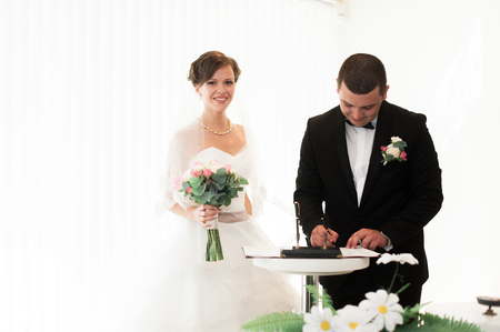 Bride and groom on marriage registration. The groom looks at the bride. Newlyweds at the wedding ceremony.の写真素材