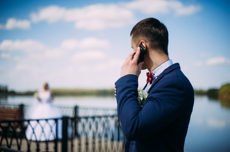 happy and beautiful groom and bride tender kiss at spring outdoors at the beach of the river under blue skyの写真素材