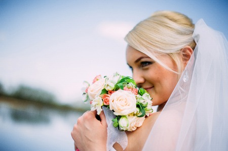 happy and beautiful groom and bride tender kiss at spring outdoors at the beach of the river under blue skyの写真素材