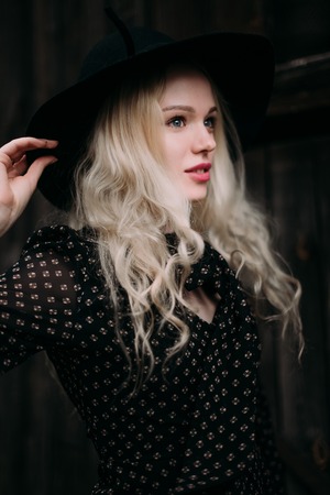 Beautiful attractive and stylish girl wearing black hat standing posing in city. Nude makeup, best daily hairstyle and great fashion glamour country style.の写真素材