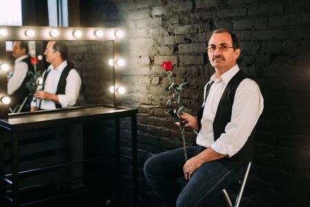 Handsome middle aged man is dressed in a white shirt and a black vest. Black background.の写真素材