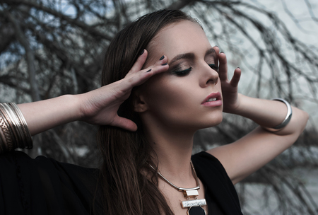Pretty brunette girls with bright makeup and pink lips wearing black posing outdoors on blue summer sky.の写真素材