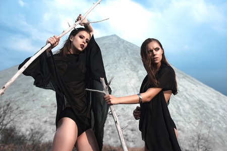 Pretty brunette girls with bright makeup and pink lips wearing black posing outdoors on blue summer sky.の写真素材