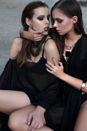 Pretty brunette girls with bright makeup and pink lips wearing black posing outdoors on blue summer sky.の写真素材