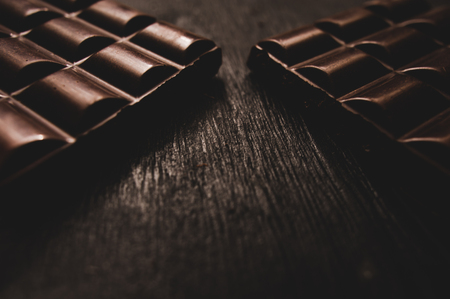 Cup of coffee with grains and chocolate on wooden table on dark backgroundの写真素材