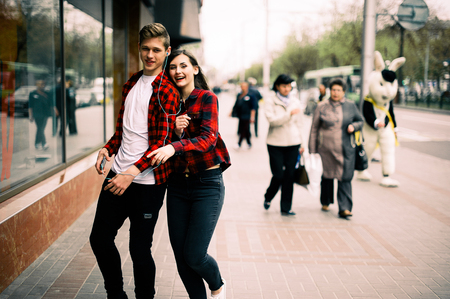 Four happy trendy teenage friends walking in the city, talking each other and smiling. Lifestyle, friendship and urban life concepts.の写真素材