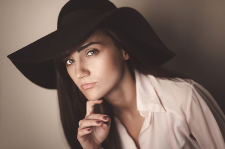 Fashion photo of beautiful lady in elegant black hat and white shirt. Studio.の写真素材