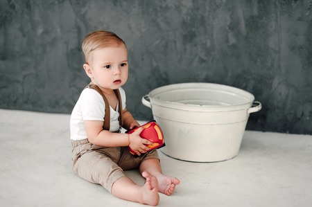 Portrait of lovely little boy happy smiling celebrating 1 year birthday. One year old european boy sitting on floor in studioの写真素材