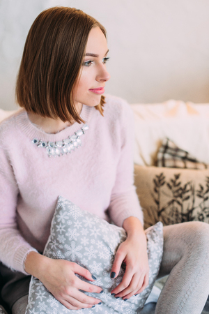 Soft photo of fresh young woman in pink tender sweater smiling. Pretty girl enjoying early sunny morning at home.の写真素材