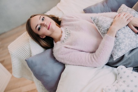 Soft photo of fresh young woman in pink tender sweater smiling. Pretty girl enjoying early sunny morning at home.の写真素材