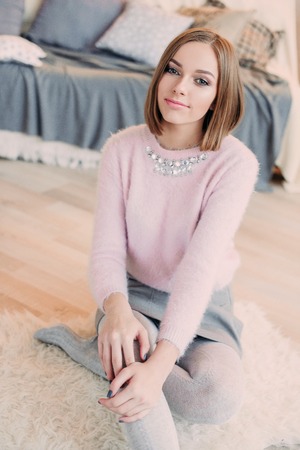 Soft photo of fresh young woman in pink tender sweater smiling. Pretty girl enjoying early sunny morning at home.の写真素材