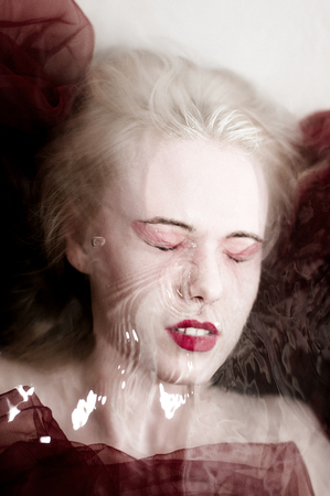 Halloween scene of an immortal female vampire in a bloody in a slaughter bath with black eyes