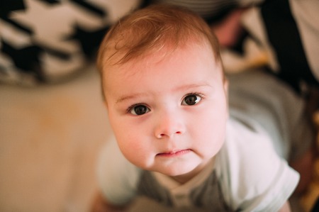 Close-up portrait of a cheerful cute baby in the crib at homeの写真素材