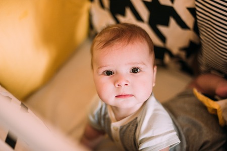 Close-up portrait of a cheerful cute baby in the crib at homeの写真素材