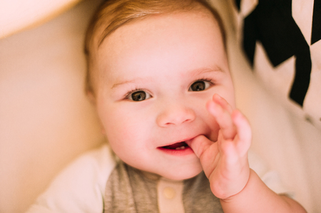 Close-up portrait of a cheerful cute baby in the crib at homeの写真素材