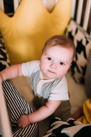 Close-up portrait of a cheerful cute baby in the crib at homeの写真素材