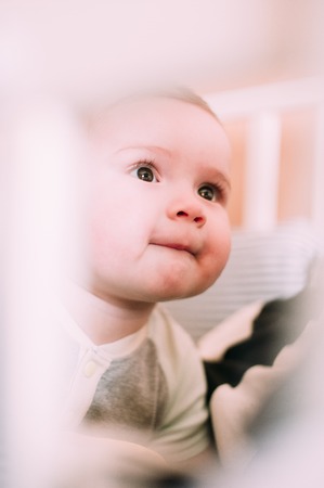 Close-up portrait of a cheerful cute baby in the crib at home