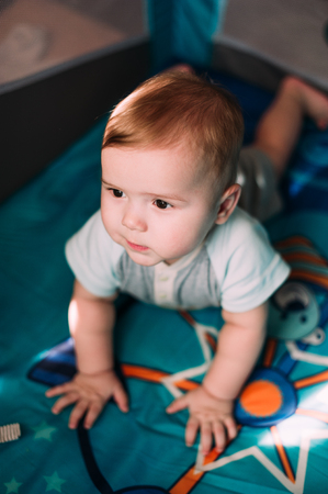 Cute little baby boy playing in colorful playpen, indoors. Beautiful child having fun at nursery.の写真素材