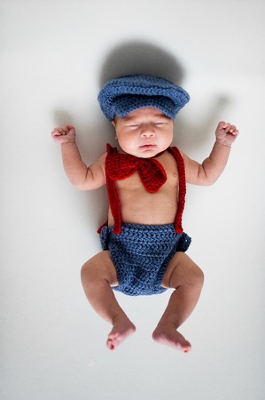 Soft picture of a beautiful baby boy laying on white beddingの写真素材