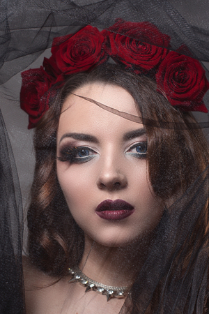 beautiful young woman with roses flower in hair. beauty girl with make-up over dark background. dark red lips.close-up fashion retouched portraitの写真素材