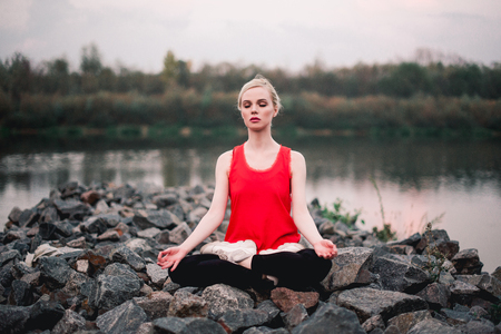 Young girl doing yoga fitness exercise outdoor near river landscape. Evening sunset, Namaste Lotus pose. Meditation and Relaxの写真素材