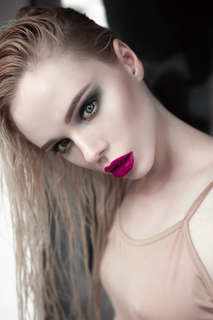 Portrait of beautiful girl model with pink lips and blue eyes with leather belt on her neck, fresh clean highlighted skin. Fashion retouched close up shot.の写真素材