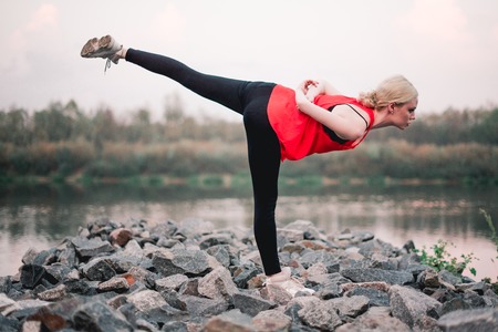 Young girl doing yoga fitness exercise outdoor near river landscape. Evening sunset, Namaste Lotus...