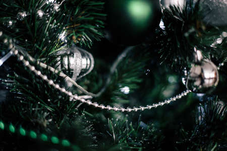 decorating christmas tree at home. Ornament close up on background of christmas tree with colorful lights and toys, copy space for textの写真素材