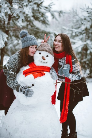 Two young teenage hipster girl friends together.Close up fashion portrait of two sisters hugs and having fun winter time,wearing sweater,best friends couple outdoors, snowy weatherの写真素材