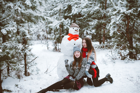 Two young teenage hipster girl friends together.Close up fashion portrait of two sisters hugs and having fun winter time,wearing sweater,best friends couple outdoors, snowy weatherの写真素材