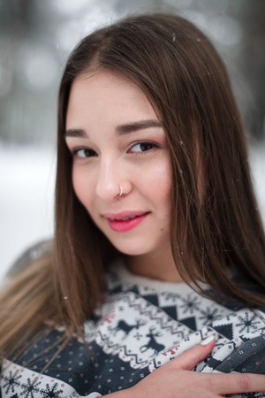 Winter portrait of young beautiful brunette woman wearing sweater. Snowing winter beauty fashion...