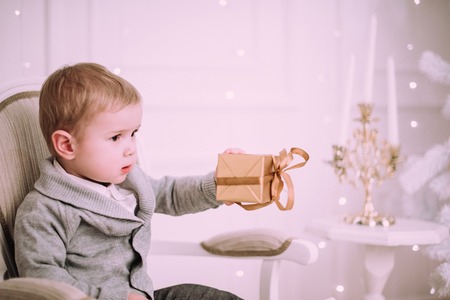 Cheerful little baby boy playing near Christmas tree, gold and beige pastel cの写真素材