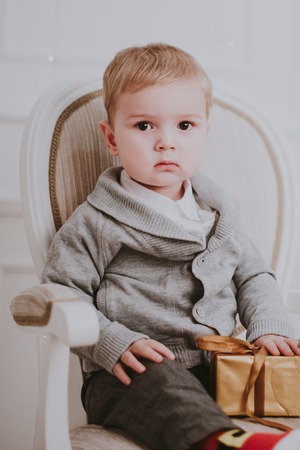 Cheerful little baby boy playing near Christmas tree, gold and beige pastel cの写真素材