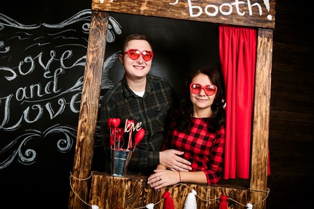 Young cheerful european couple in love embracing and kissing in decorated studio, light pastel colors, dating.の写真素材