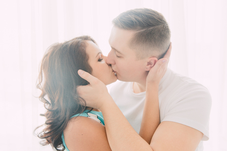 Young cheerful european couple in love embracing and kissing in decorated studio, light pastel colors, dating.の写真素材