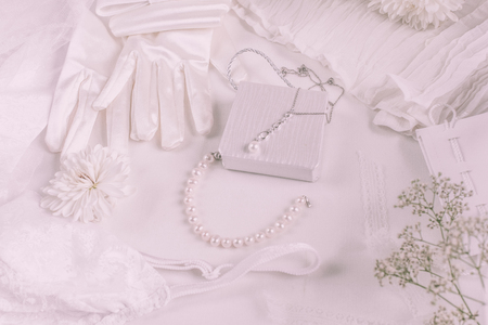 White bridal accessories for wedding background with pearls, white satin ribbons and lace, gloves, bracelet,flat lay for fashion blog, top viewの写真素材