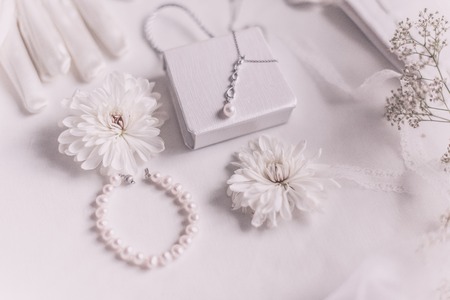 White bridal accessories for wedding background with pearls, white satin ribbons and lace, gloves, bracelet,flat lay for fashion blog, top viewの写真素材