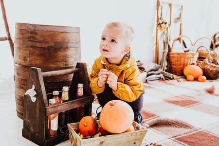 Cool trendy hipster boy 2 years old wears yellow jacket posing at the decorated photozone of autumn...