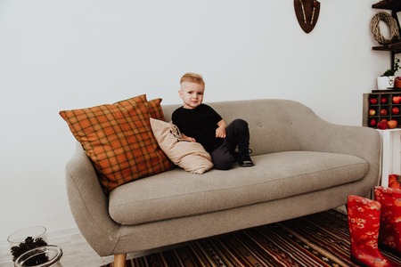 Cool trendy hipster boy 2 years old wears yellow jacket posing at the decorated photozone of autumn...